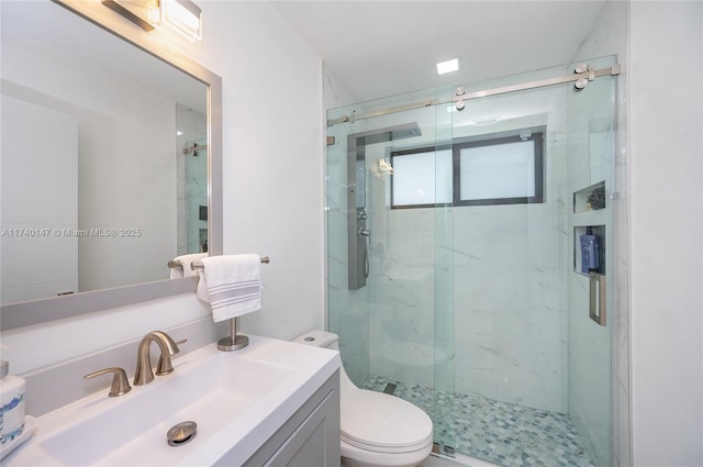 bathroom with walk in shower, vanity, and toilet