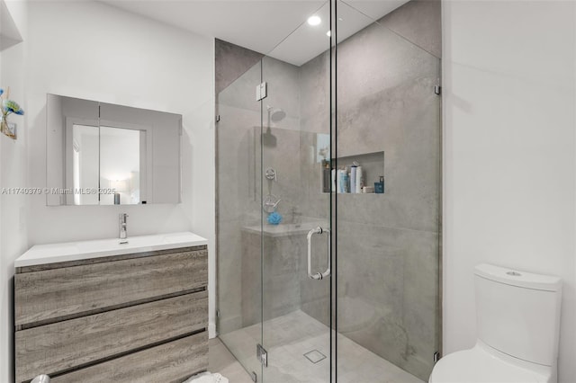 bathroom featuring vanity, toilet, and a shower with shower door