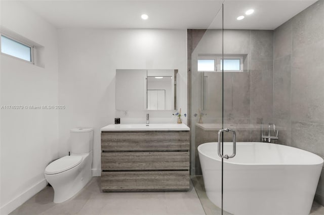 bathroom featuring vanity, toilet, a bath, and a wealth of natural light