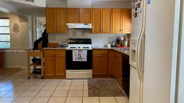 kitchen with electric stove, backsplash, light tile patterned floors, and white refrigerator with ice dispenser