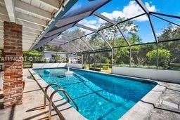 view of swimming pool with a patio and glass enclosure