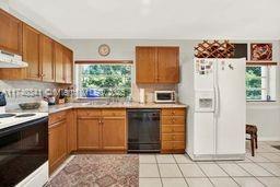 kitchen featuring electric stove, a healthy amount of sunlight, white refrigerator with ice dispenser, and dishwasher