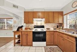 kitchen featuring electric stove, light tile patterned floors, decorative backsplash, and sink