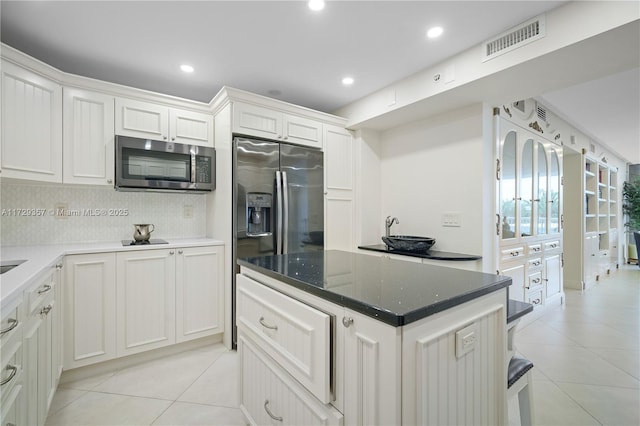 kitchen with white cabinetry, appliances with stainless steel finishes, decorative backsplash, and light tile patterned floors