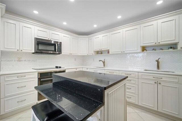 kitchen featuring a center island, sink, light tile patterned floors, and black appliances