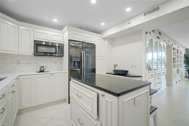 kitchen with light tile patterned floors, decorative backsplash, stainless steel appliances, and white cabinets