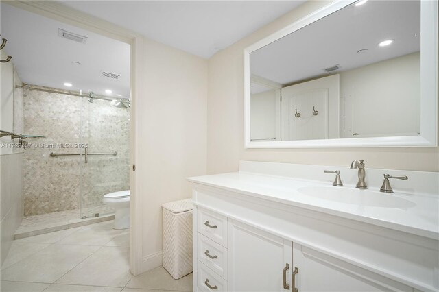 bathroom featuring vanity, toilet, tile patterned flooring, and a tile shower