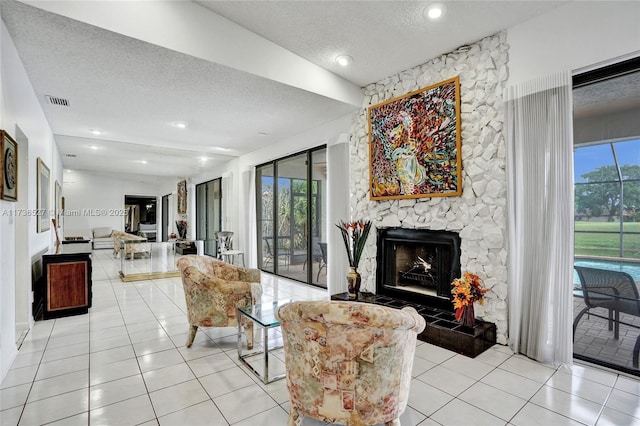 living room featuring light tile patterned floors, a stone fireplace, a textured ceiling, and a healthy amount of sunlight