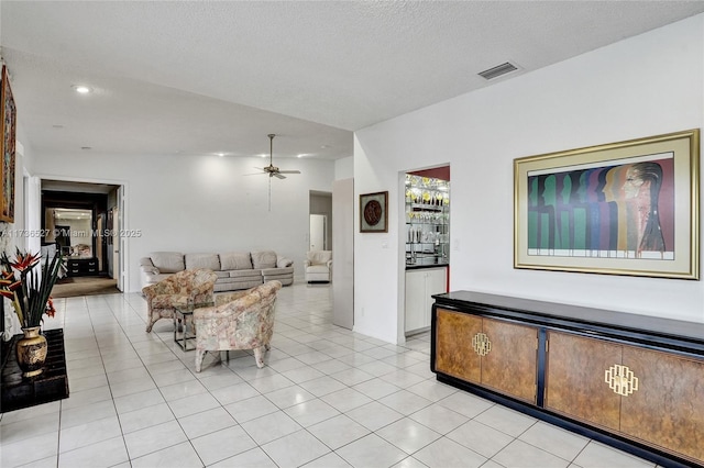 living area with light tile patterned floors, a textured ceiling, visible vents, and a ceiling fan