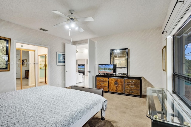 bedroom with carpet, visible vents, ceiling fan, and a textured ceiling