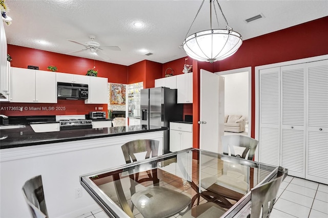 dining room with light tile patterned floors, ceiling fan, a textured ceiling, and visible vents