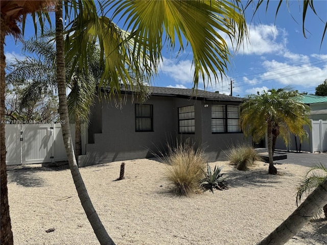 view of property exterior featuring stucco siding, fence, and a gate