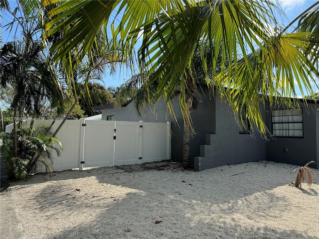 view of home's exterior with a gate, fence, and stucco siding