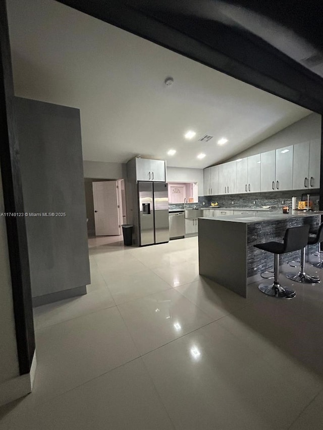 15281 SW 153rd St, Miami, FL 33187 - kitchen featuring white cabinets, lofted ceiling, appliances with stainless steel finishes, a breakfast bar, and a peninsula
