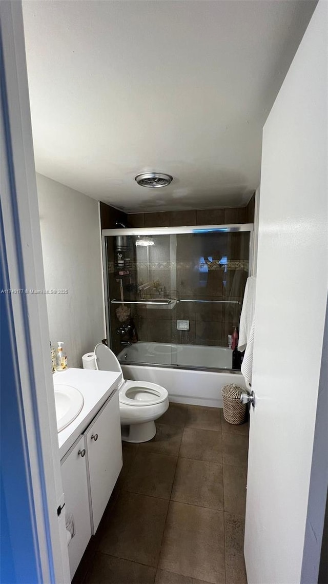 full bathroom with toilet, tile patterned floors, vanity, and bath / shower combo with glass door