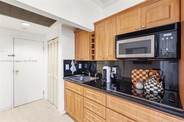 kitchen with crown molding, sink, backsplash, and black appliances