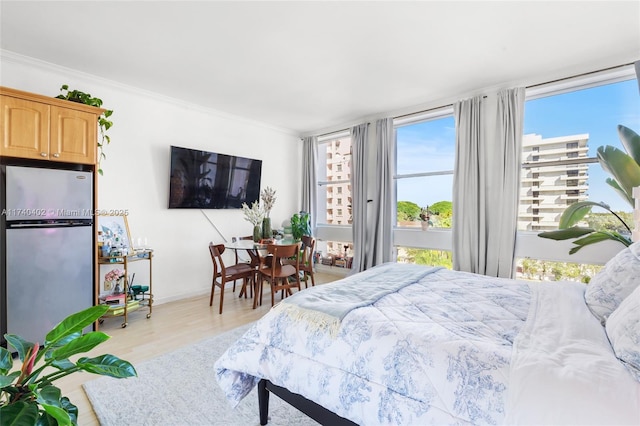 bedroom with ornamental molding, stainless steel refrigerator, and light hardwood / wood-style flooring