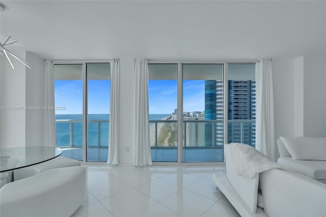 tiled living room featuring a water view, a wall of windows, and plenty of natural light