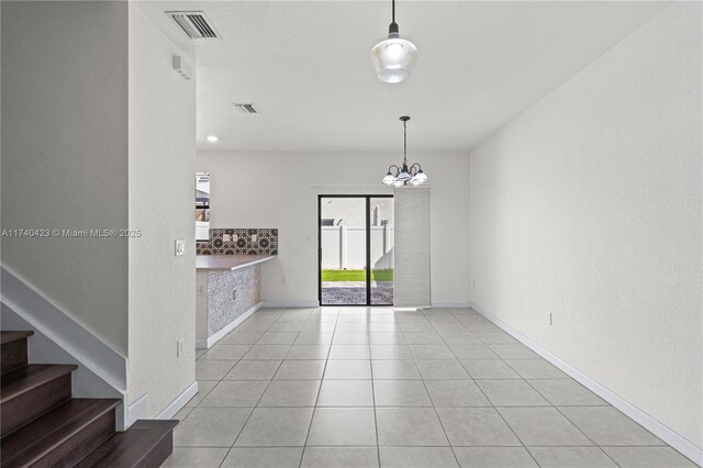 tiled empty room with a chandelier