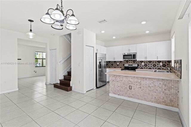 kitchen with stainless steel appliances, sink, white cabinets, and kitchen peninsula