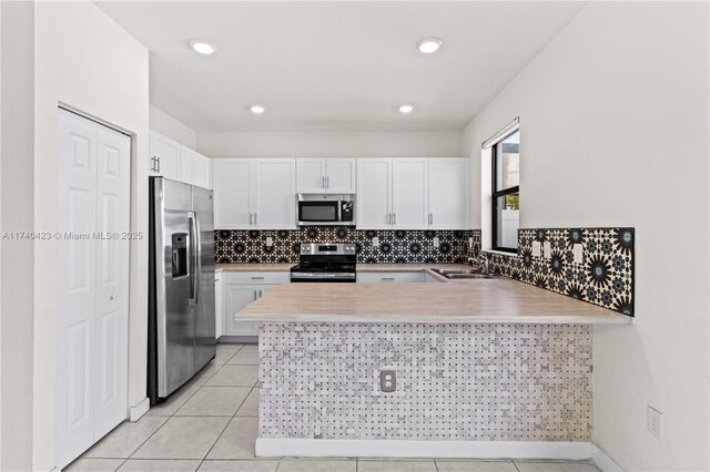 kitchen with sink, white cabinetry, backsplash, stainless steel appliances, and kitchen peninsula