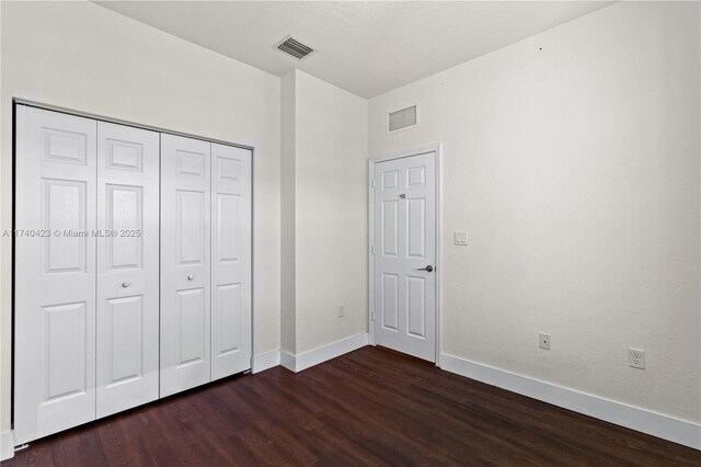 unfurnished bedroom with dark hardwood / wood-style flooring and a closet