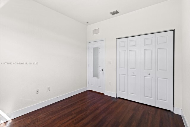 unfurnished bedroom featuring dark hardwood / wood-style floors and a closet