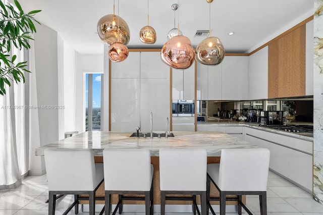 kitchen with pendant lighting, stainless steel gas stovetop, a center island, and white cabinets