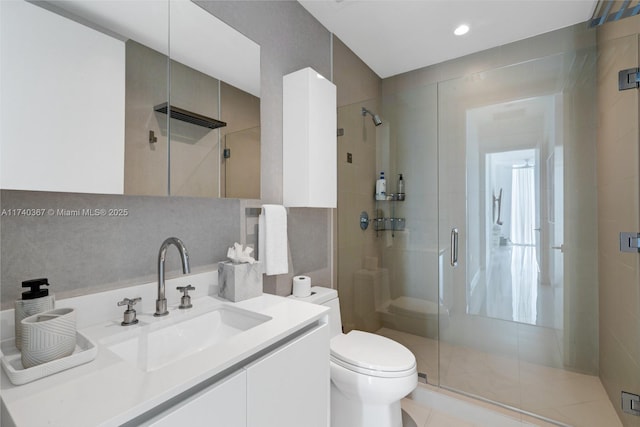 bathroom featuring vanity, toilet, tile walls, and a shower with shower door