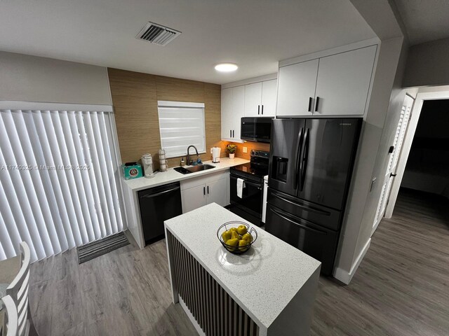 222 SW 8th St, Dania Beach, FL 33004 - kitchen featuring sink, black appliances, a center island, hardwood / wood-style flooring, and white cabinets