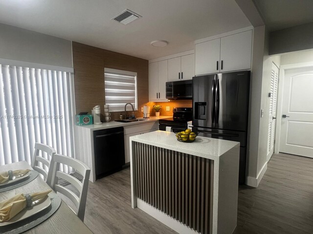 222 SW 8th St, Dania Beach, FL 33004 - kitchen with sink, electric range oven, a center island, black dishwasher, and white cabinets