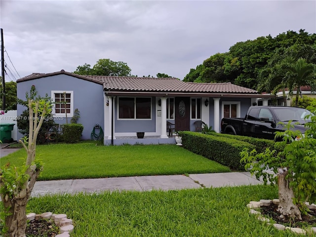 view of front of house featuring a tile roof, a front yard, and stucco siding