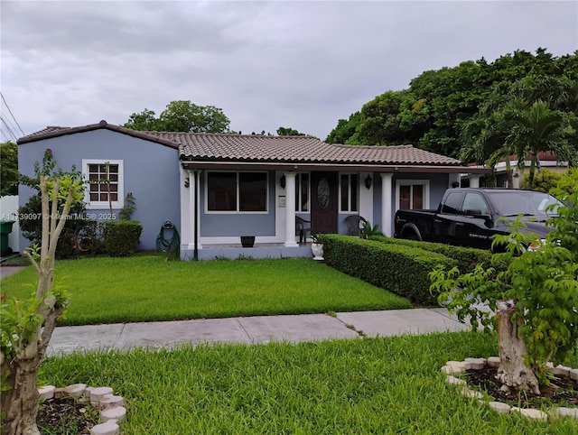 view of front of home with a tile roof, a front lawn, and stucco siding