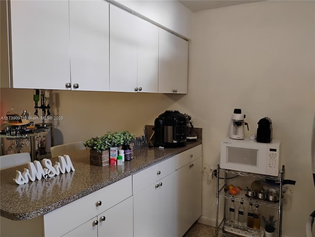 kitchen featuring dark stone countertops and white cabinets