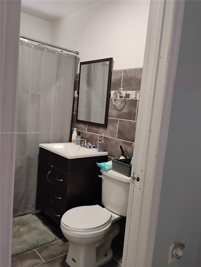 bathroom with tile patterned flooring, vanity, tile walls, and toilet