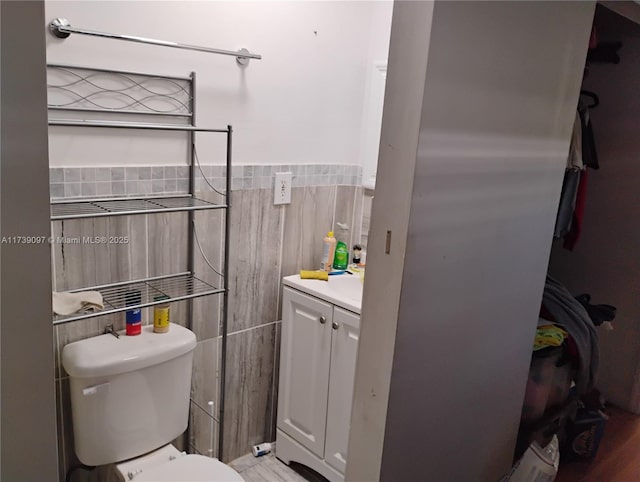 bathroom with vanity, toilet, and tile walls