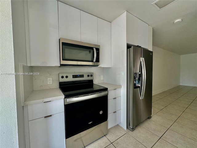 kitchen featuring white cabinetry, stainless steel appliances, tasteful backsplash, and light tile patterned floors