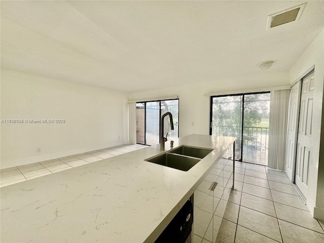 kitchen featuring light tile patterned flooring, light stone countertops, and sink