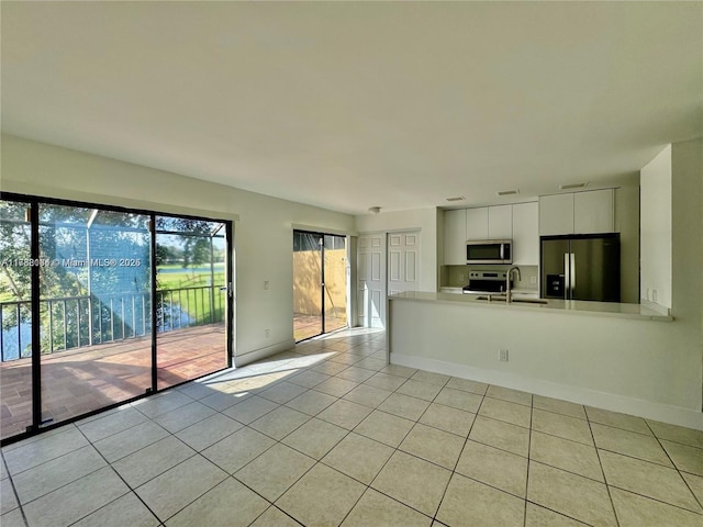 kitchen featuring light tile patterned flooring, sink, kitchen peninsula, stainless steel appliances, and white cabinets