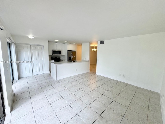 kitchen featuring stainless steel appliances, white cabinetry, light tile patterned floors, and kitchen peninsula