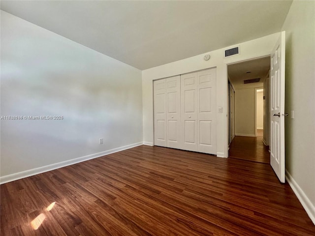 unfurnished bedroom with dark hardwood / wood-style flooring and a closet