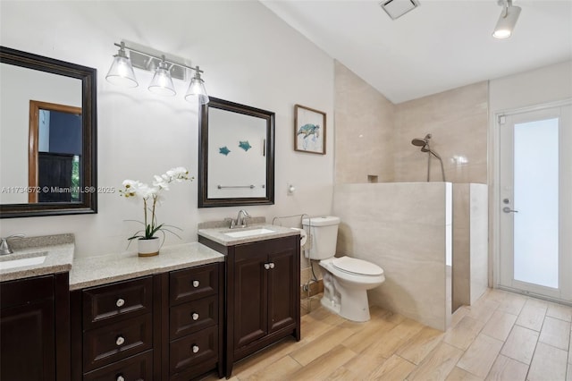 bathroom featuring a tile shower, vanity, hardwood / wood-style flooring, and toilet