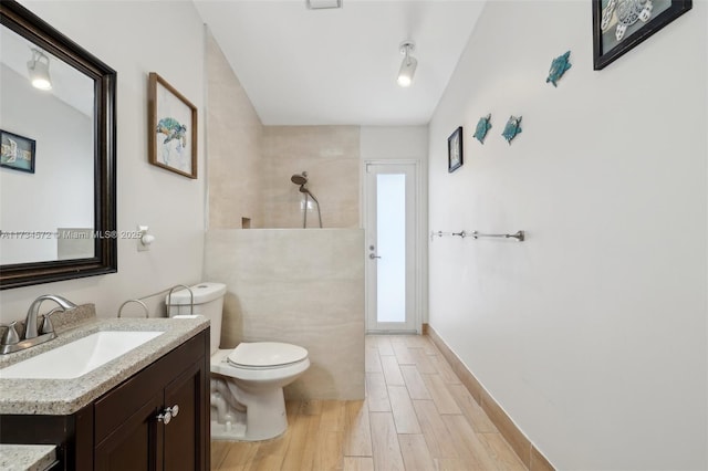 bathroom featuring vanity, toilet, and a tile shower