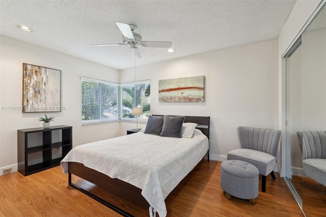 bedroom featuring hardwood / wood-style flooring, a textured ceiling, ceiling fan, and a closet