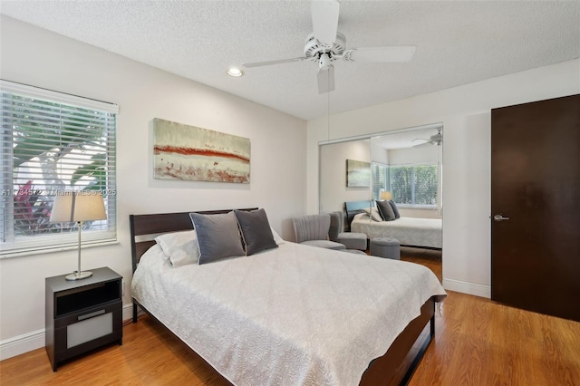 bedroom featuring multiple windows, ceiling fan, hardwood / wood-style floors, and a textured ceiling