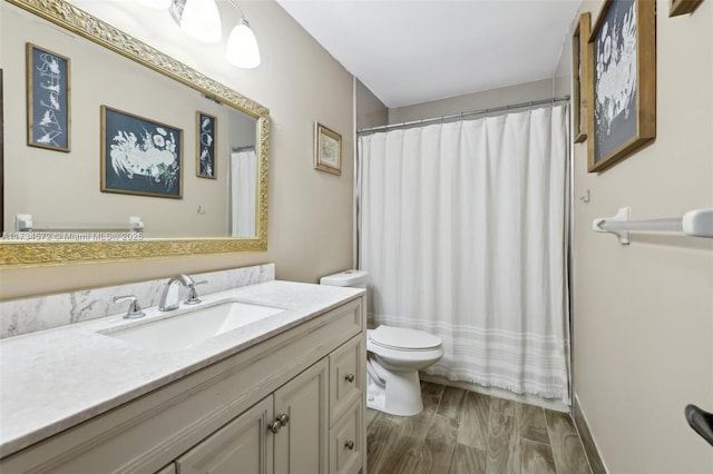 bathroom featuring hardwood / wood-style flooring, vanity, toilet, and walk in shower