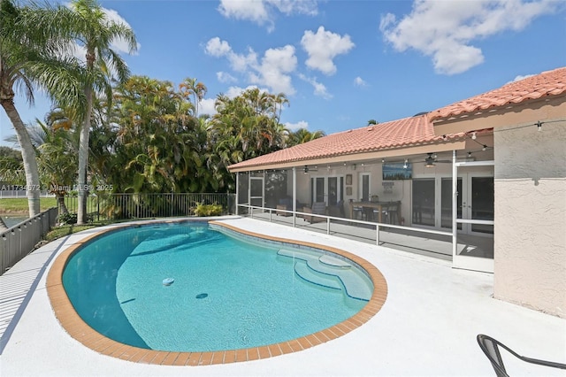 view of swimming pool featuring a sunroom, a patio, and ceiling fan