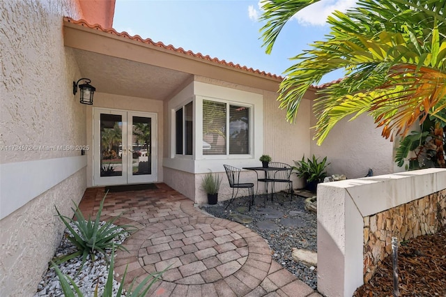 view of exterior entry with a patio area and french doors