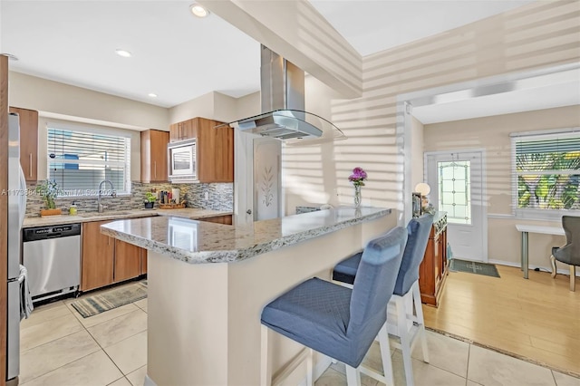 kitchen featuring sink, stainless steel appliances, ventilation hood, light stone countertops, and decorative backsplash