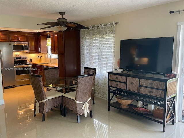 dining area featuring ceiling fan, sink, and a textured ceiling